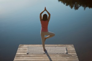 Woman meditating on her deck on tree position.